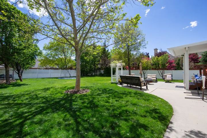 Expansive lawn area with mature trees and a white privacy fence