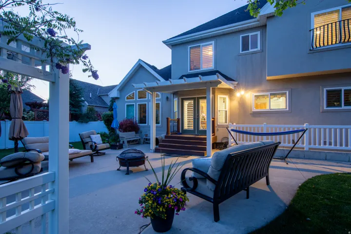 Spacious concrete patio featuring a pergola, stucco exterior, and a white picket fence