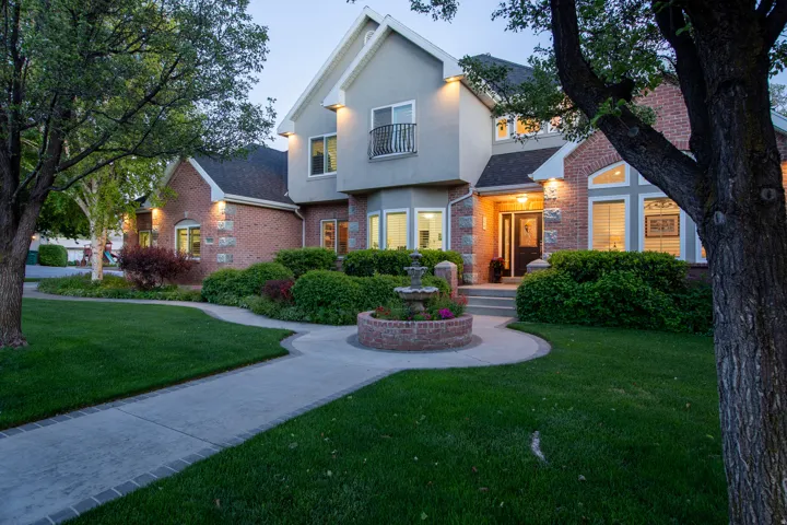 Stately brick and stucco exterior with a prominent front entrance, featuring a decorative fountain at the end of a winding concrete path