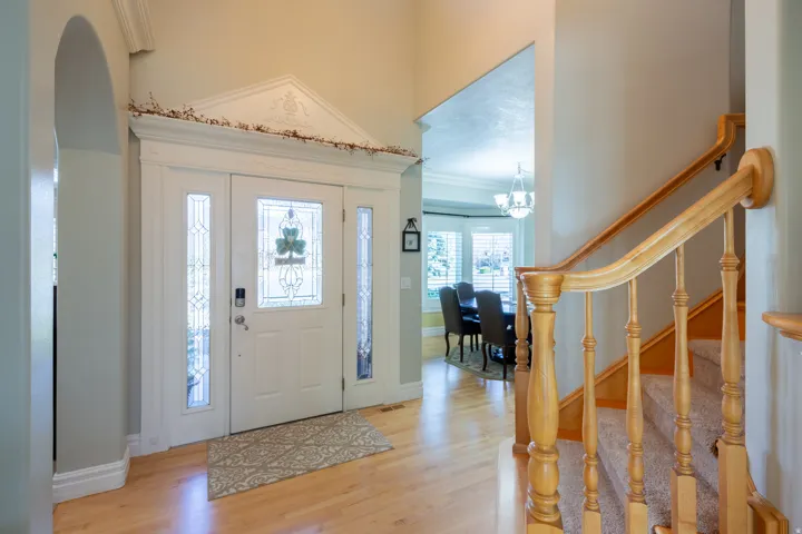 Entryway featuring wood-finish flooring, a grand staircase with wood banister, and a decorative front door with sidelights