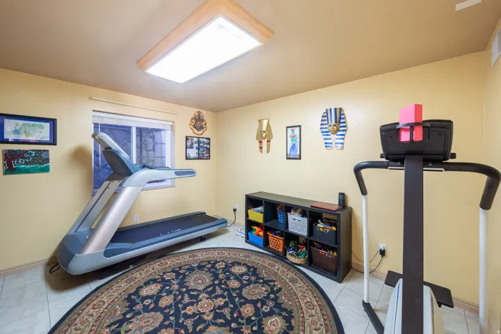 Versatile room featuring light-toned walls, tile flooring, and a large recessed ceiling light fixture