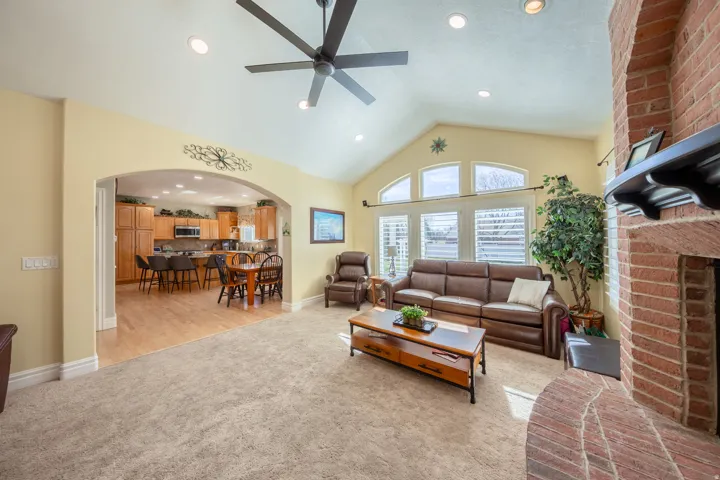 Vaulted living room with a prominent red brick fireplace featuring a dark wood mantel