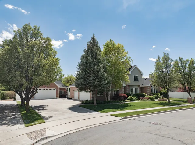 Traditional-style residence featuring a brick and siding exterior, multiple two-car garages, and a paved driveway