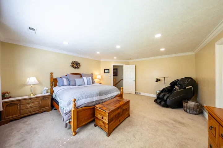 Spacious room featuring neutral carpeting, crown molding, recessed lighting, and a white paneled door