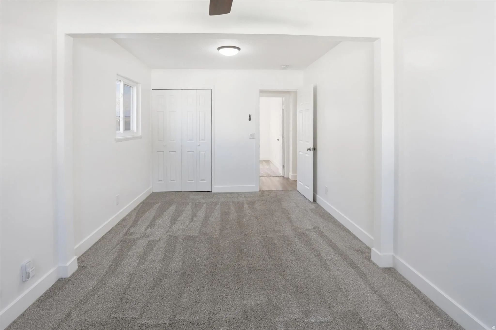 Hallway with dark colored carpet and baseboards
