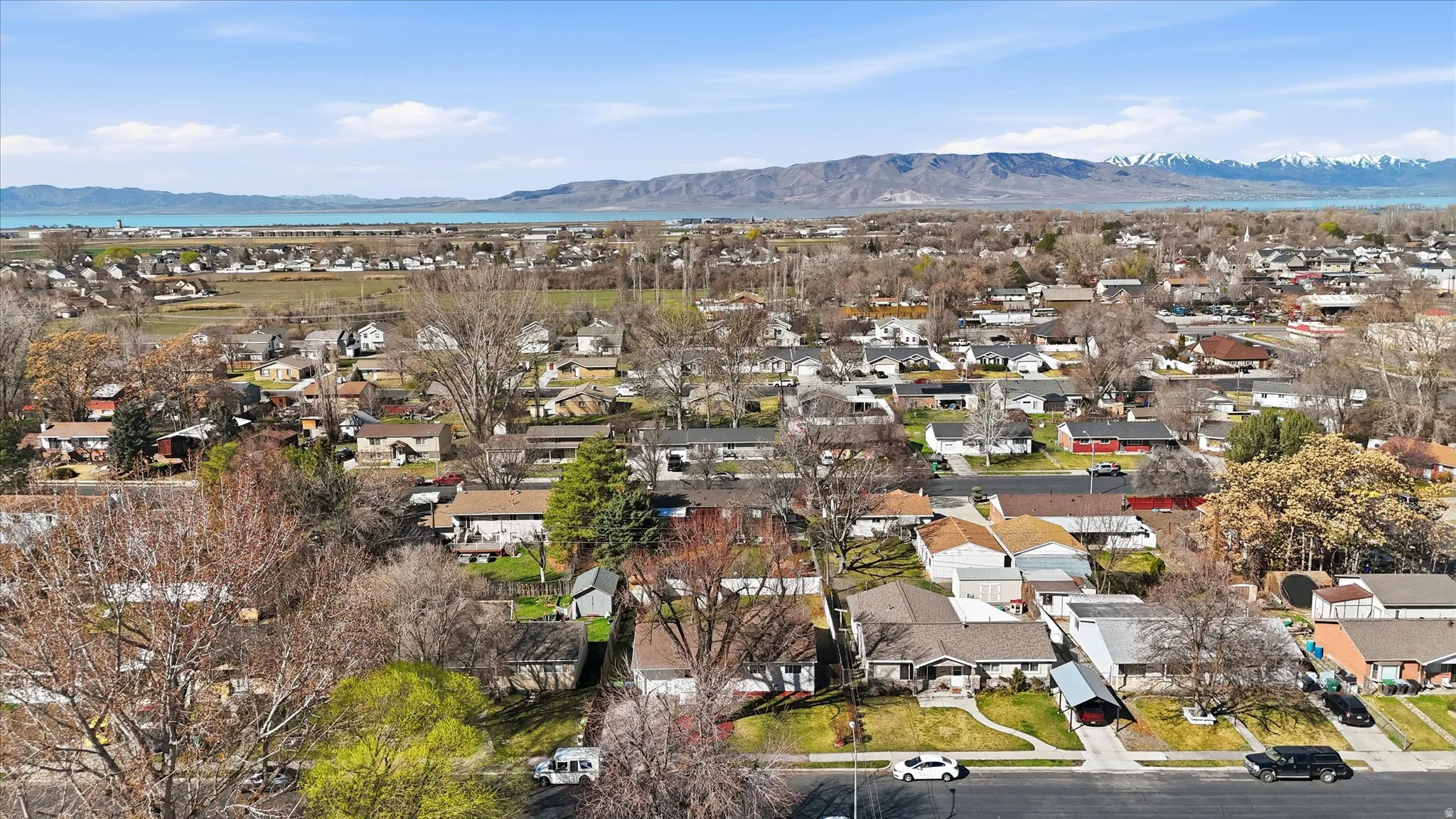 Aerial view of property and surrounding area featuring nearby suburban area and a mountain backdrop