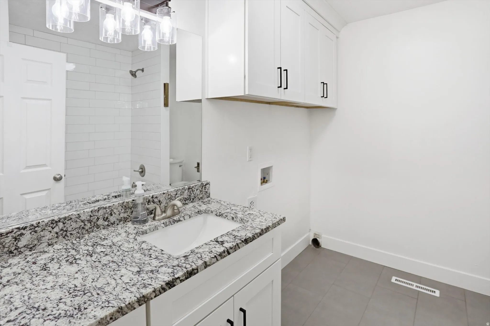 Bathroom with vanity, light tile patterned flooring, and a shower