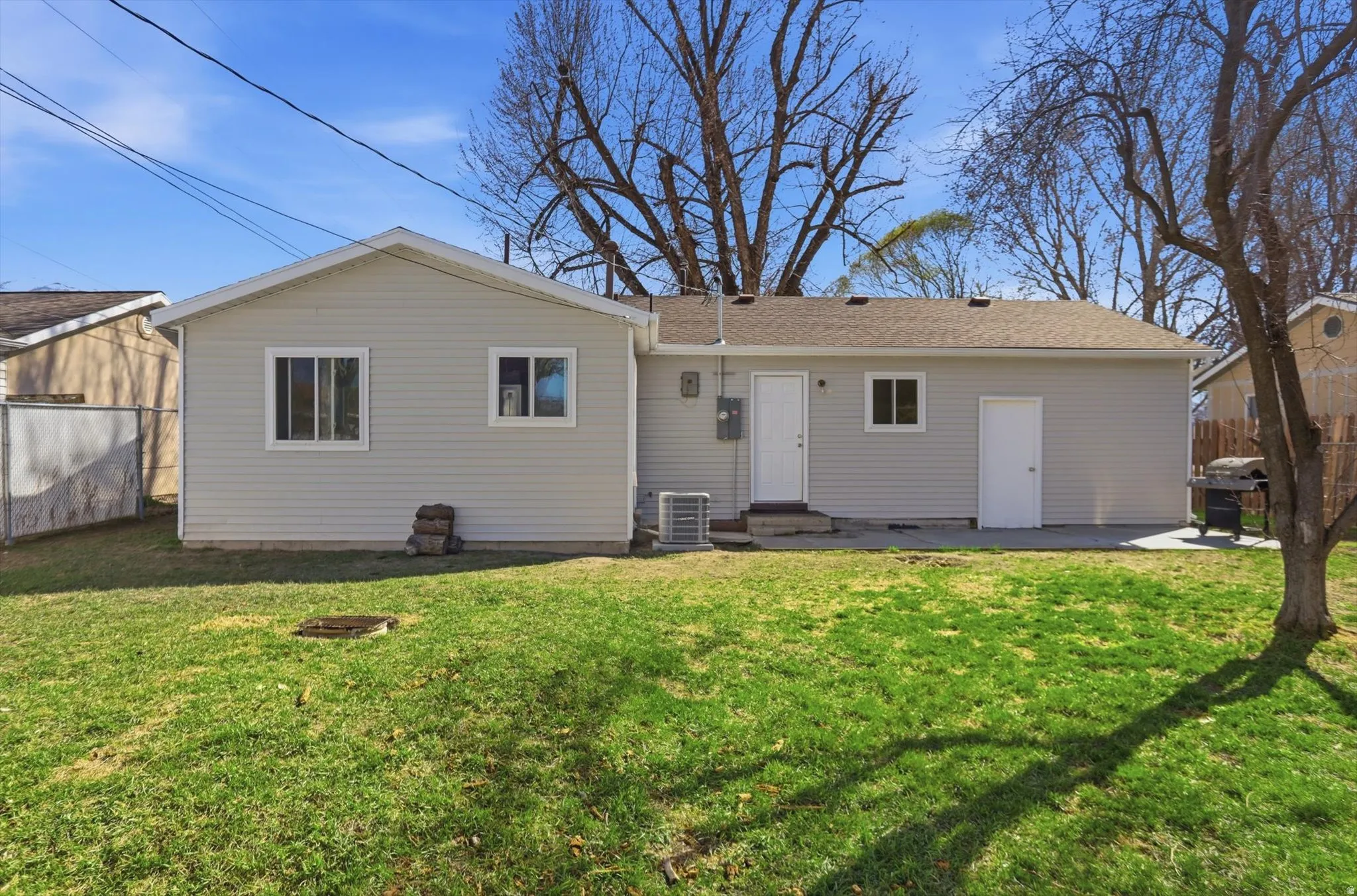 Rear view of house with a patio, entry steps, and a shingled roof