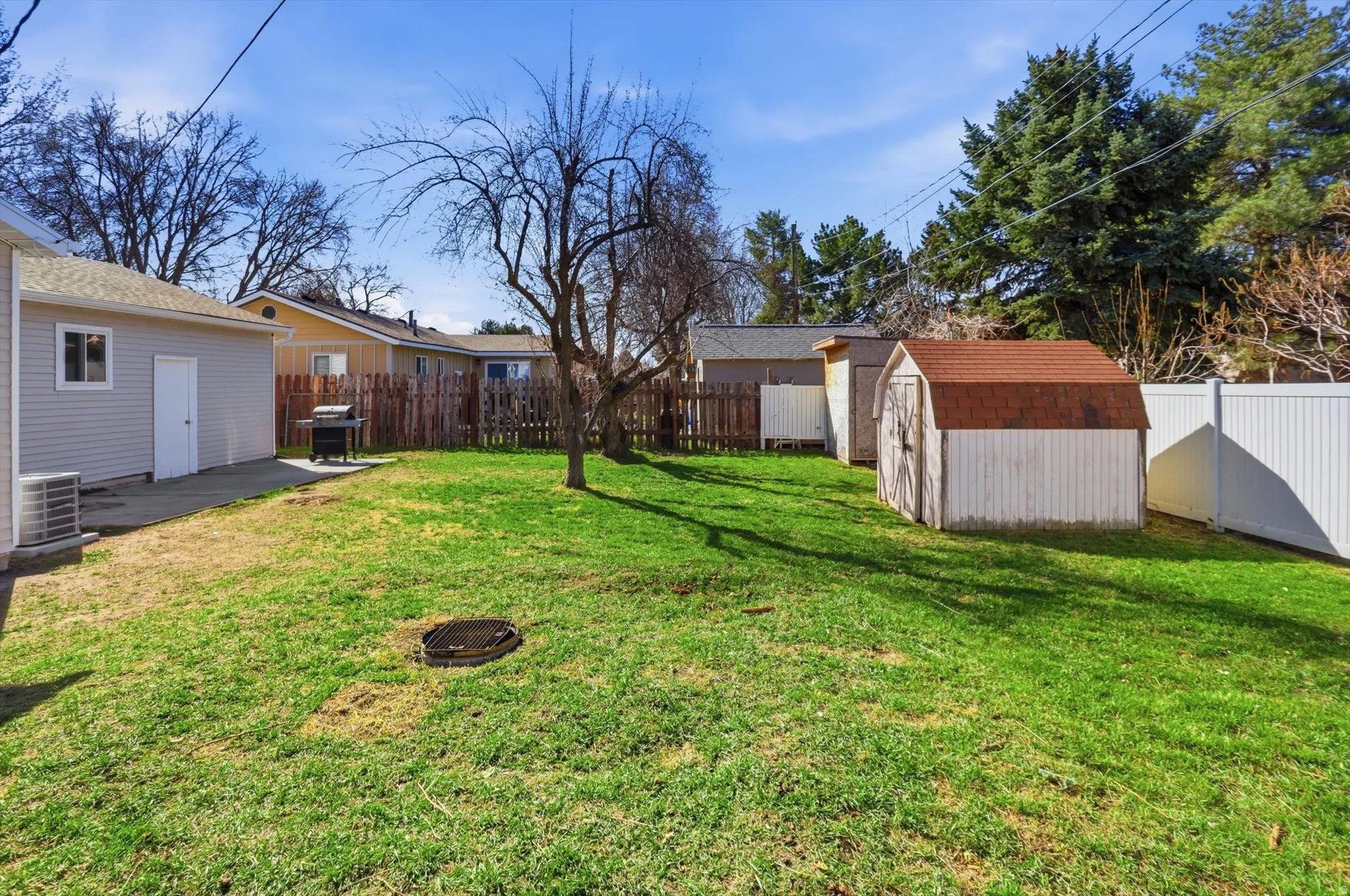 Fenced backyard featuring a shed, a patio area, and an outdoor fire pit