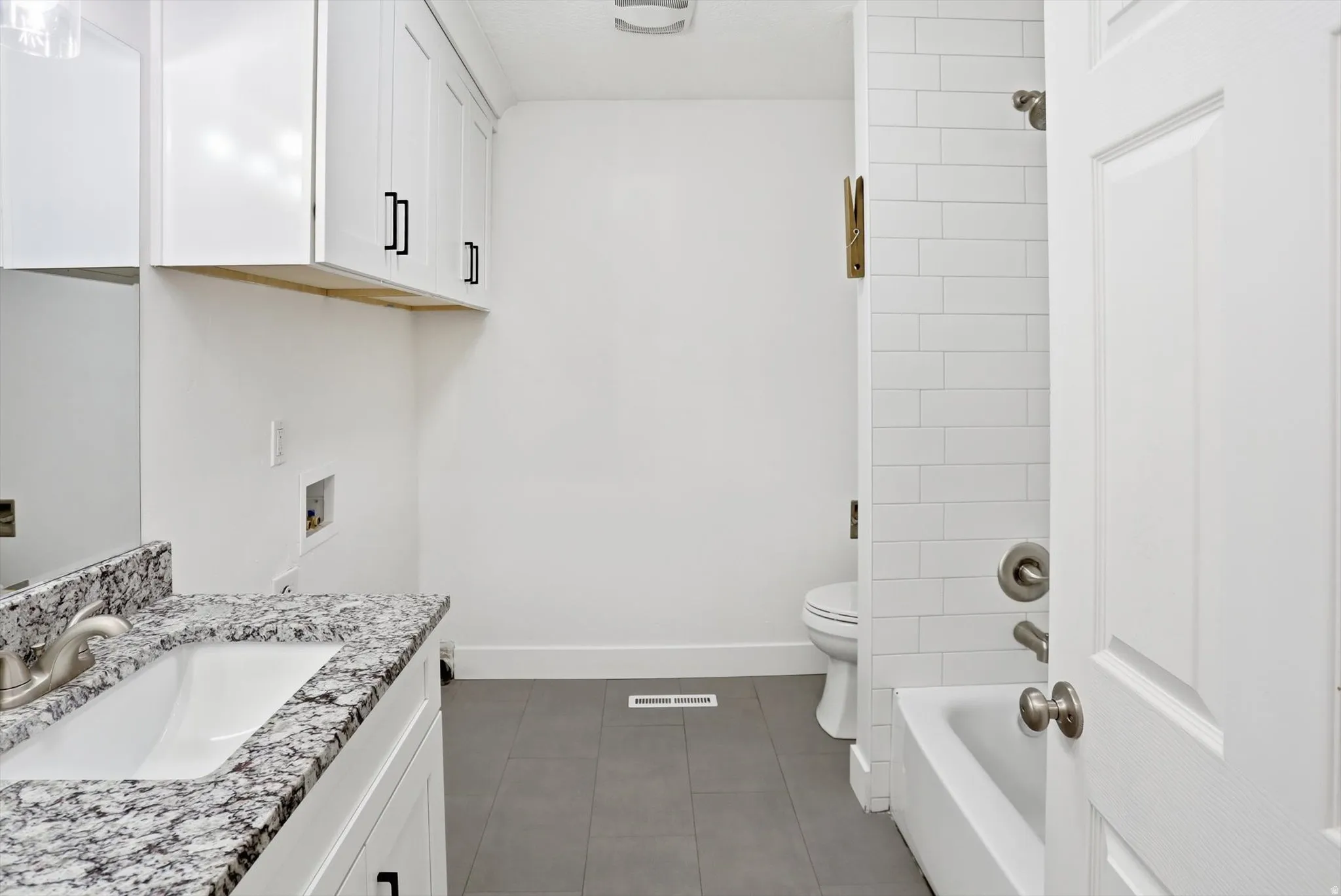 Full bathroom featuring vanity,  shower combination, and dark tile patterned floors