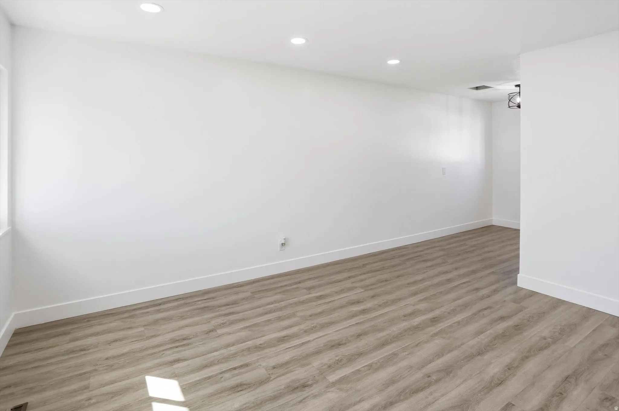 Empty room with light wood-type flooring and recessed lighting