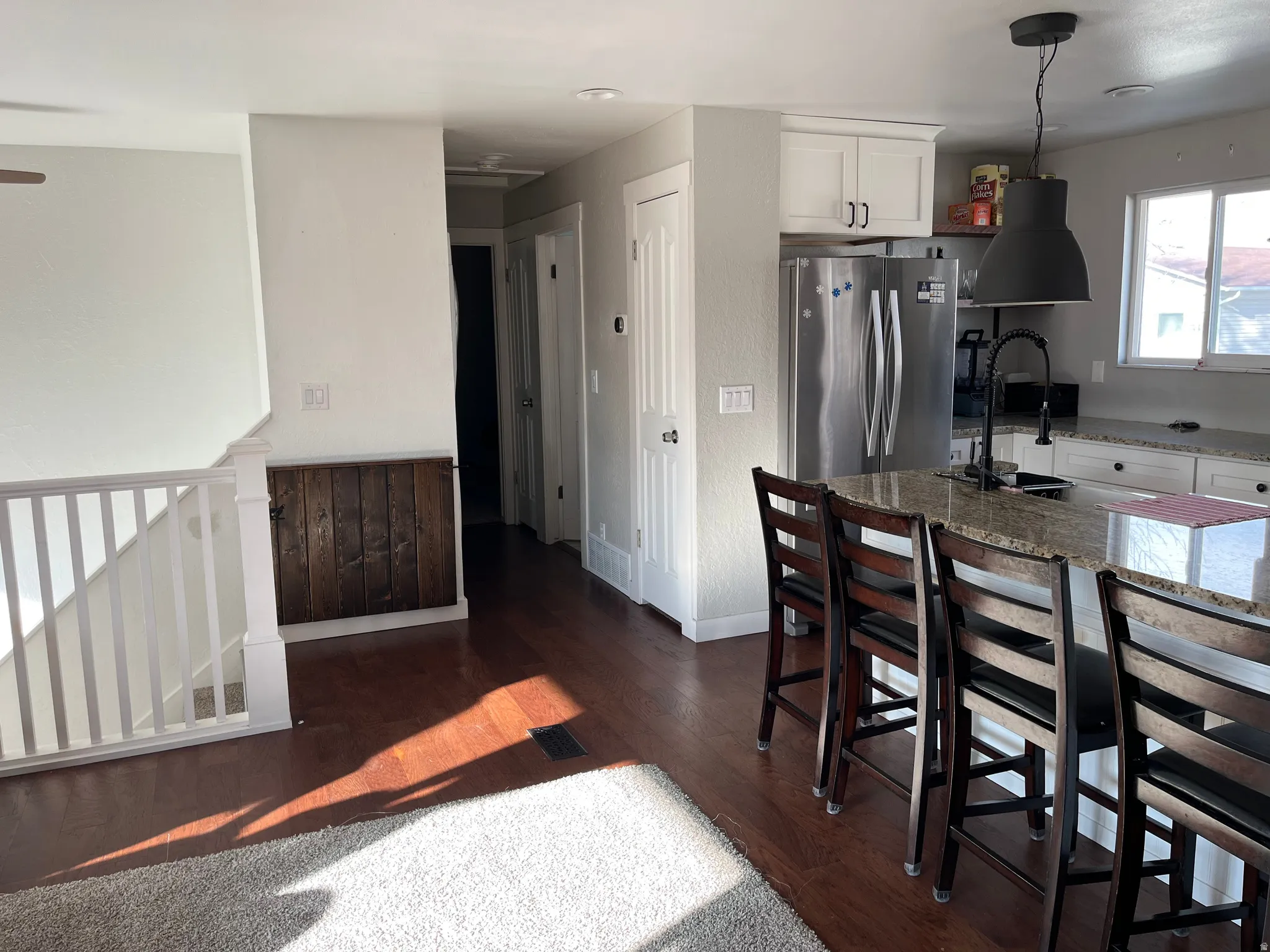 Kitchen with white cabinetry, dark stone countertops, freestanding refrigerator, dark wood-type flooring, and pendant lighting