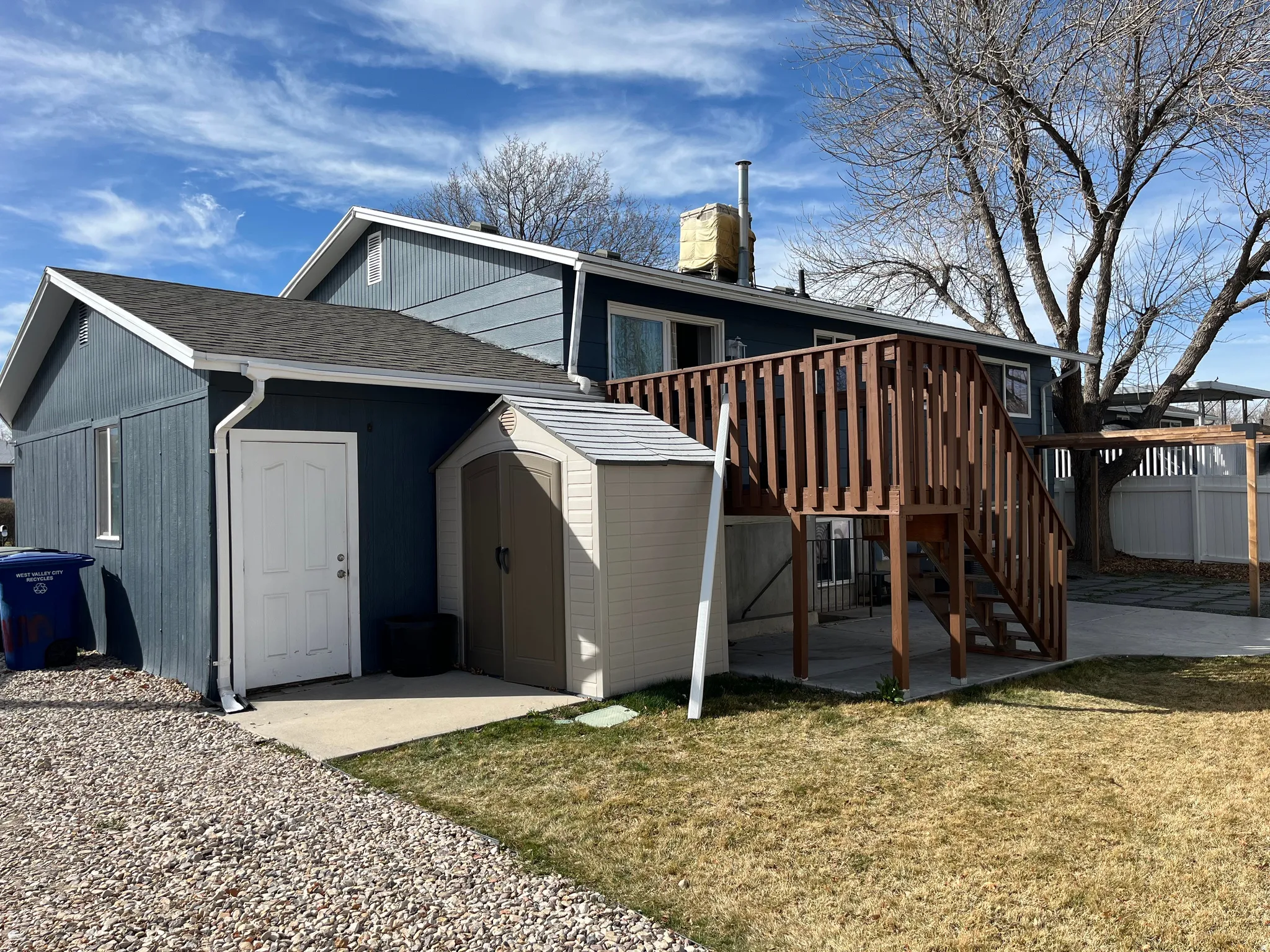 Back of property with a storage shed, a lawn, a shingled roof, and a patio