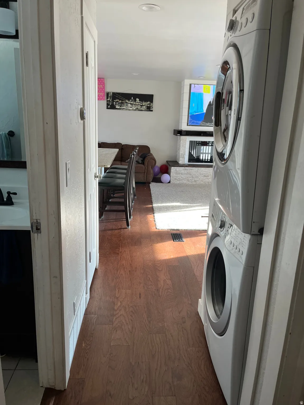 Laundry area with dark wood-style flooring and stacked washer and dryer