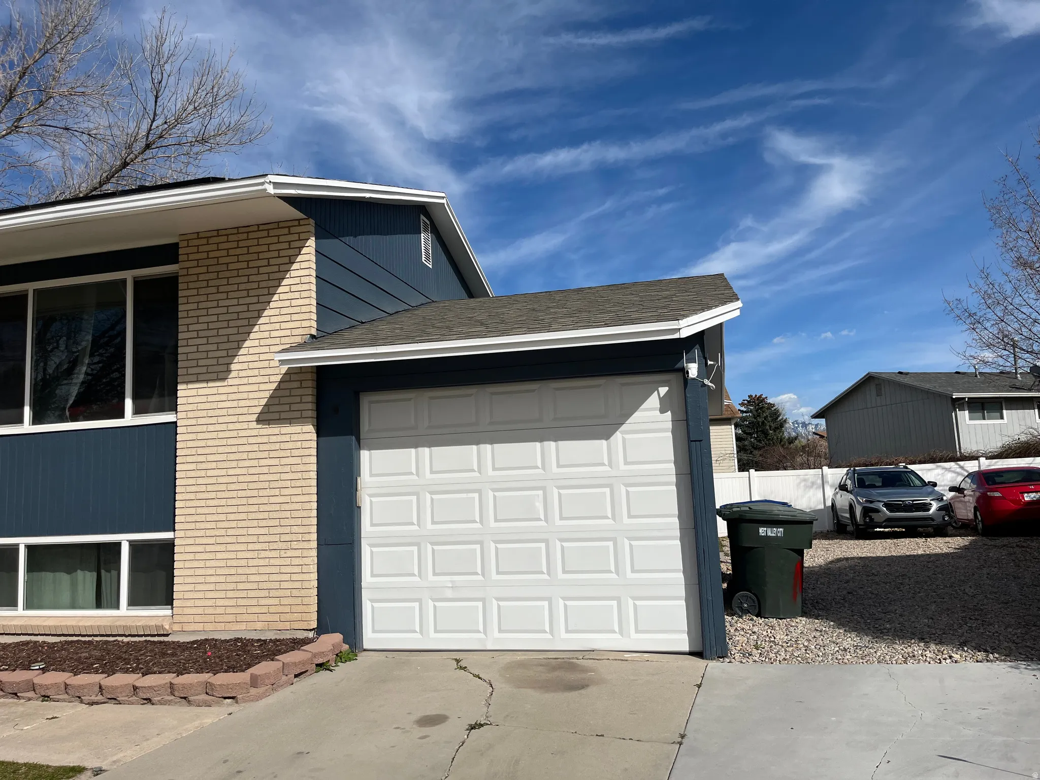 View of property exterior with brick siding, a garage, and concrete driveway