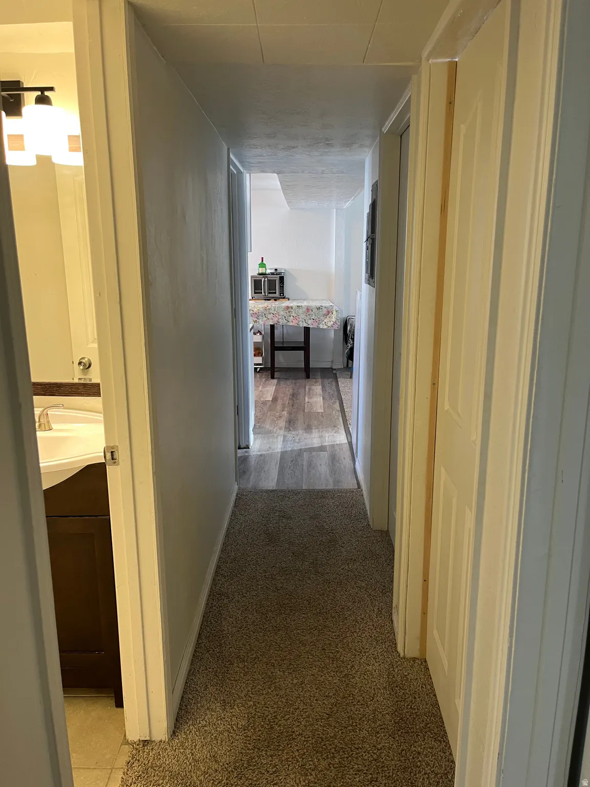 Corridor featuring light colored carpet and baseboards