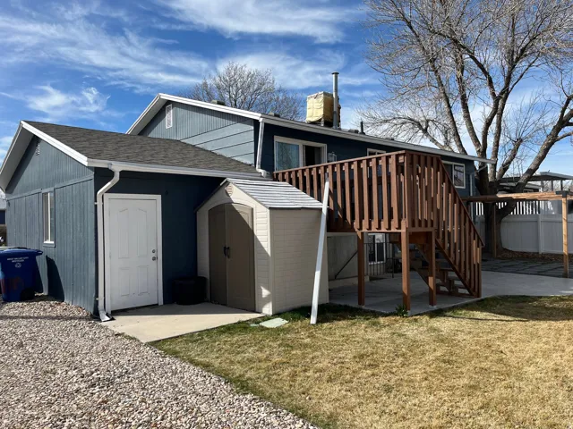Back of property with a storage shed, a lawn, a shingled roof, and a patio