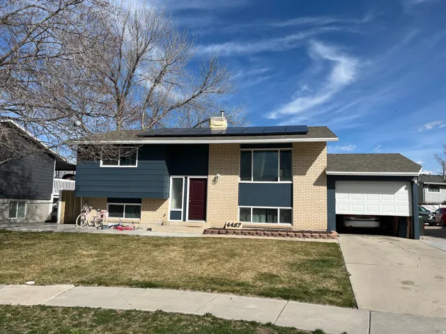 Split foyer home with brick siding, a chimney, concrete driveway, an attached garage, and a front yard