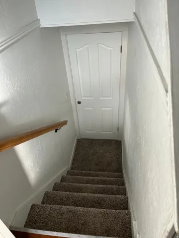 Stairway featuring a textured wall and carpet floors
