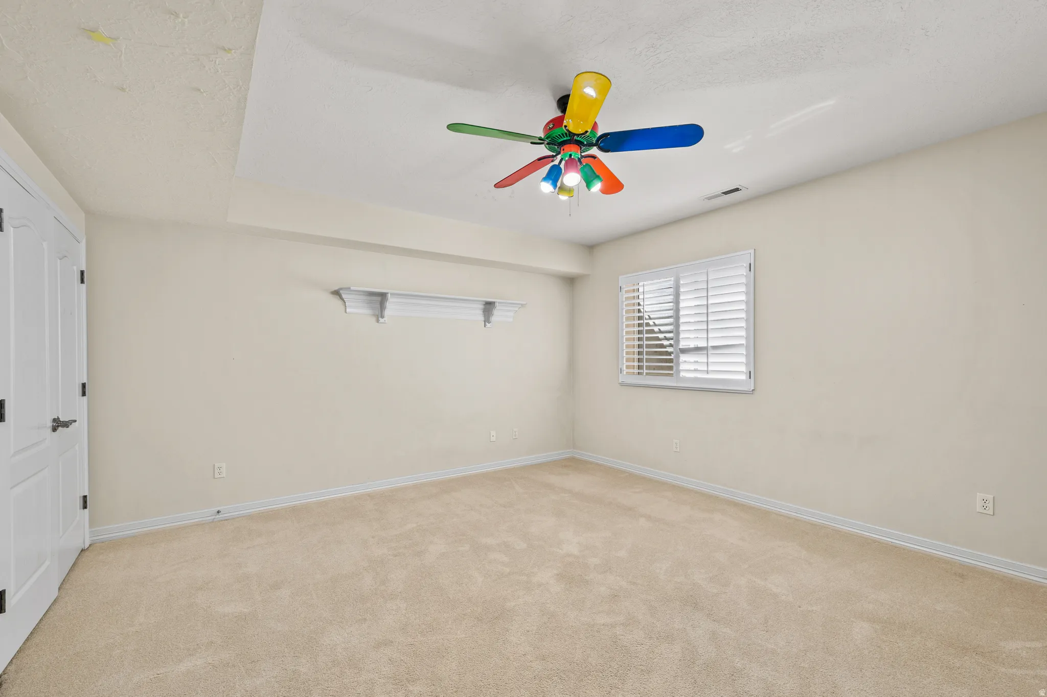 Spare room featuring light colored carpet, a ceiling fan, and a textured ceiling