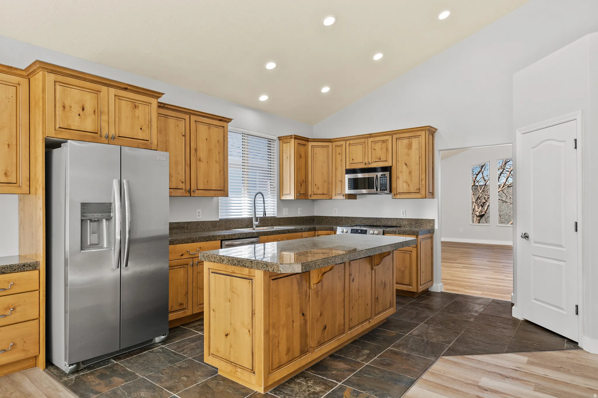 Kitchen featuring tile countertops, stainless steel appliances, a kitchen bar, a kitchen island, and recessed lighting