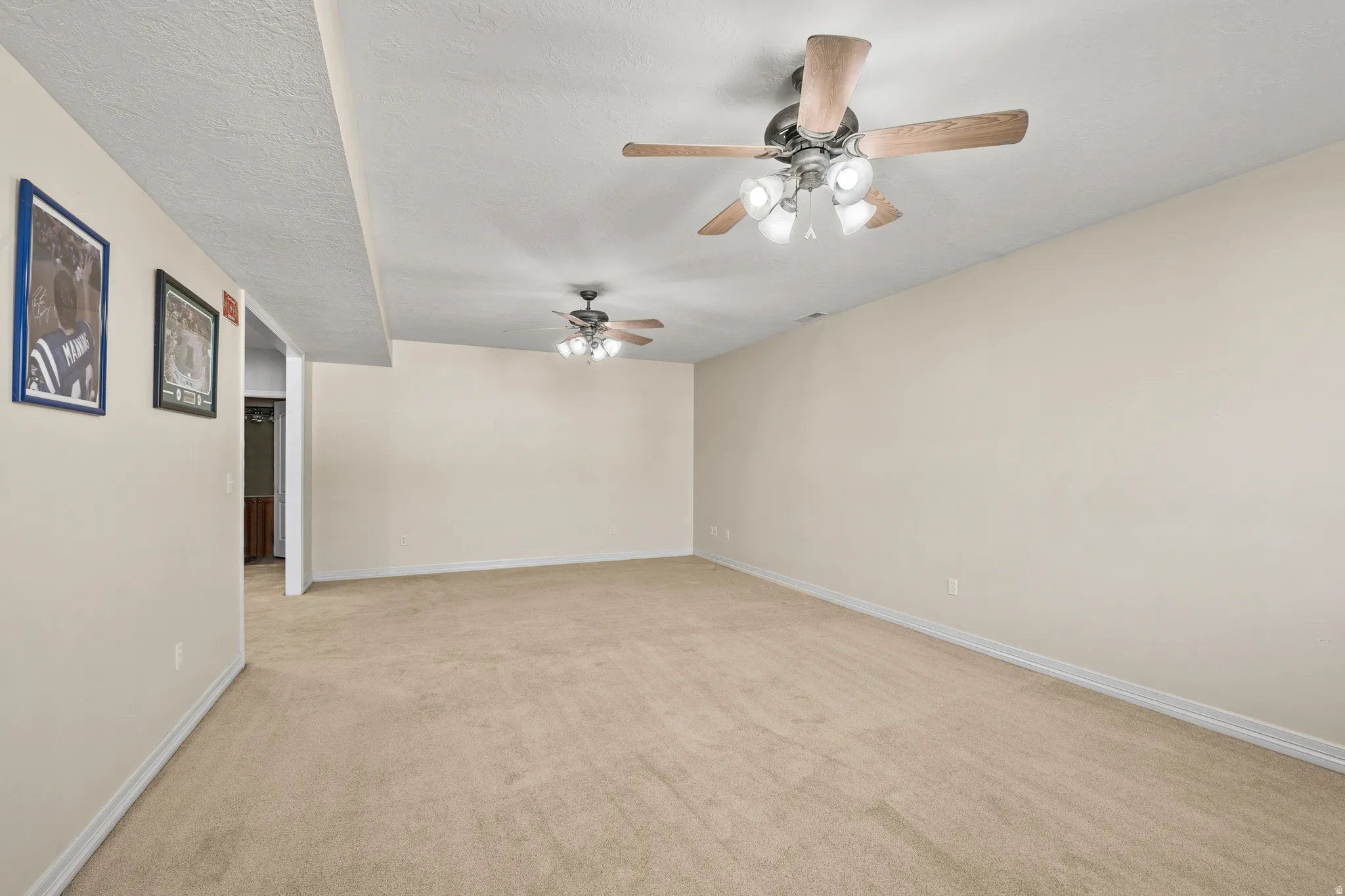Spare room featuring ceiling fan, light colored carpet, and a textured ceiling
