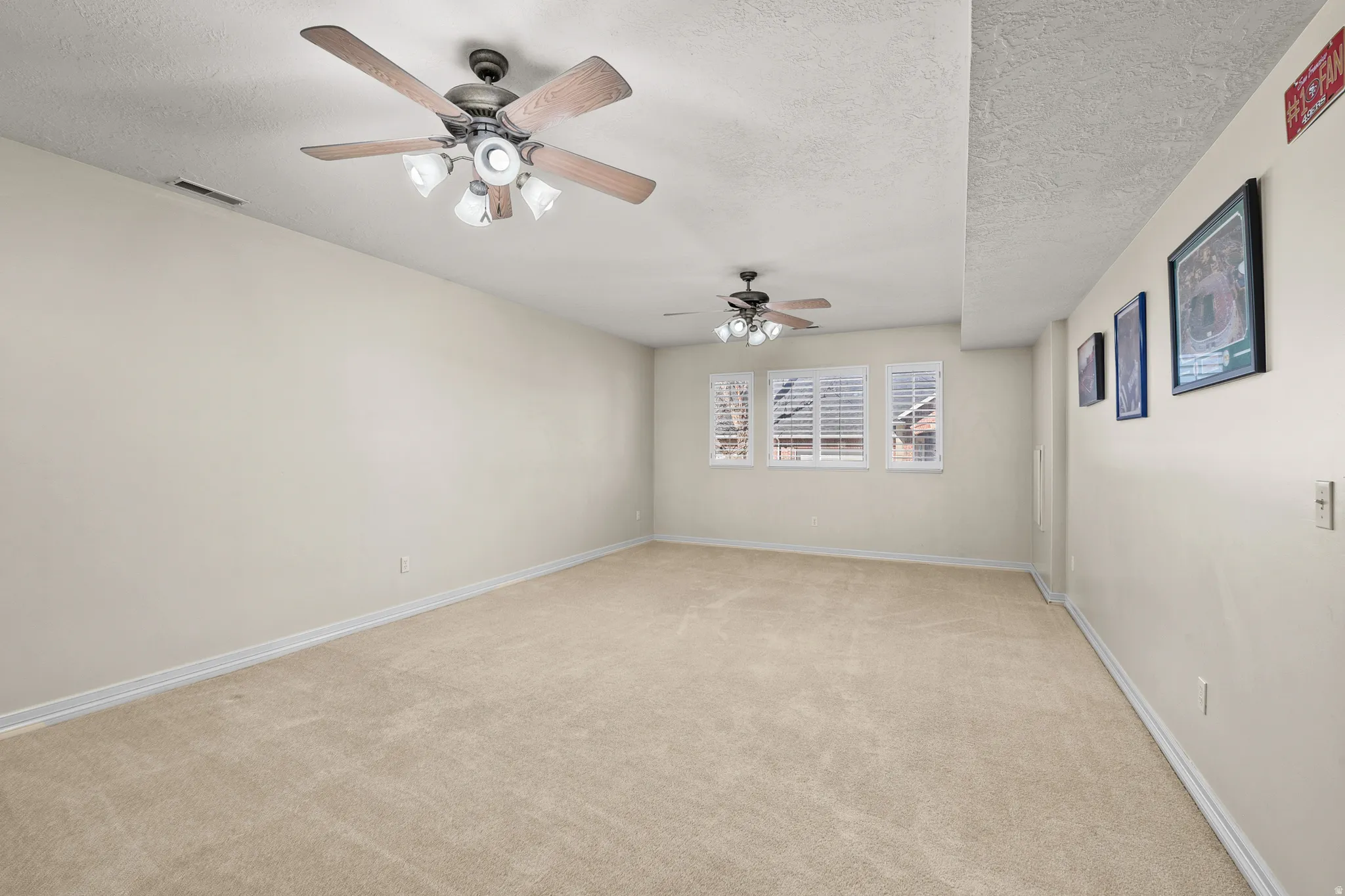 Spare room featuring light colored carpet, a textured ceiling, and ceiling fan