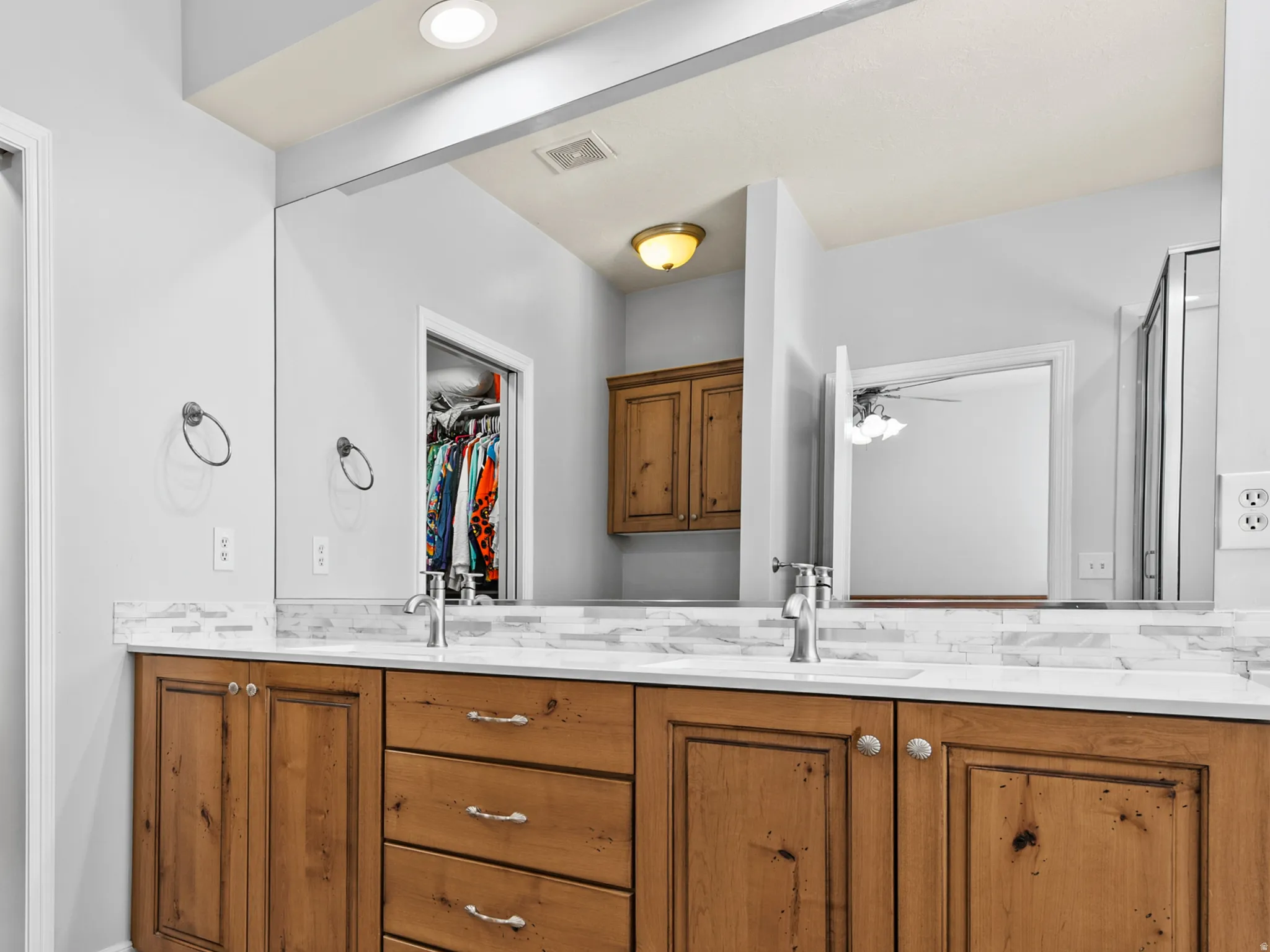 Full bathroom featuring double vanity, a walk-in closet, and light tile patterned floors
