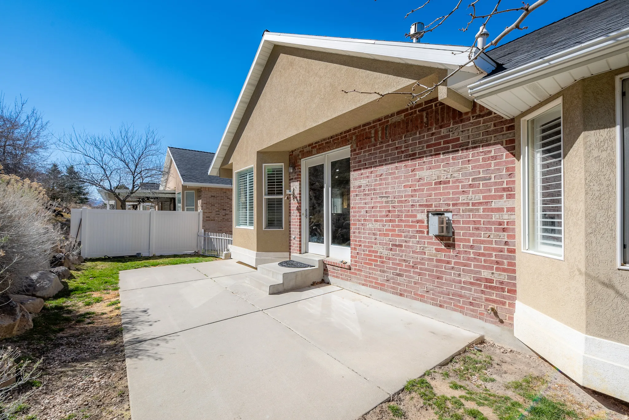 Back of property with a patio, brick siding, and stucco siding
