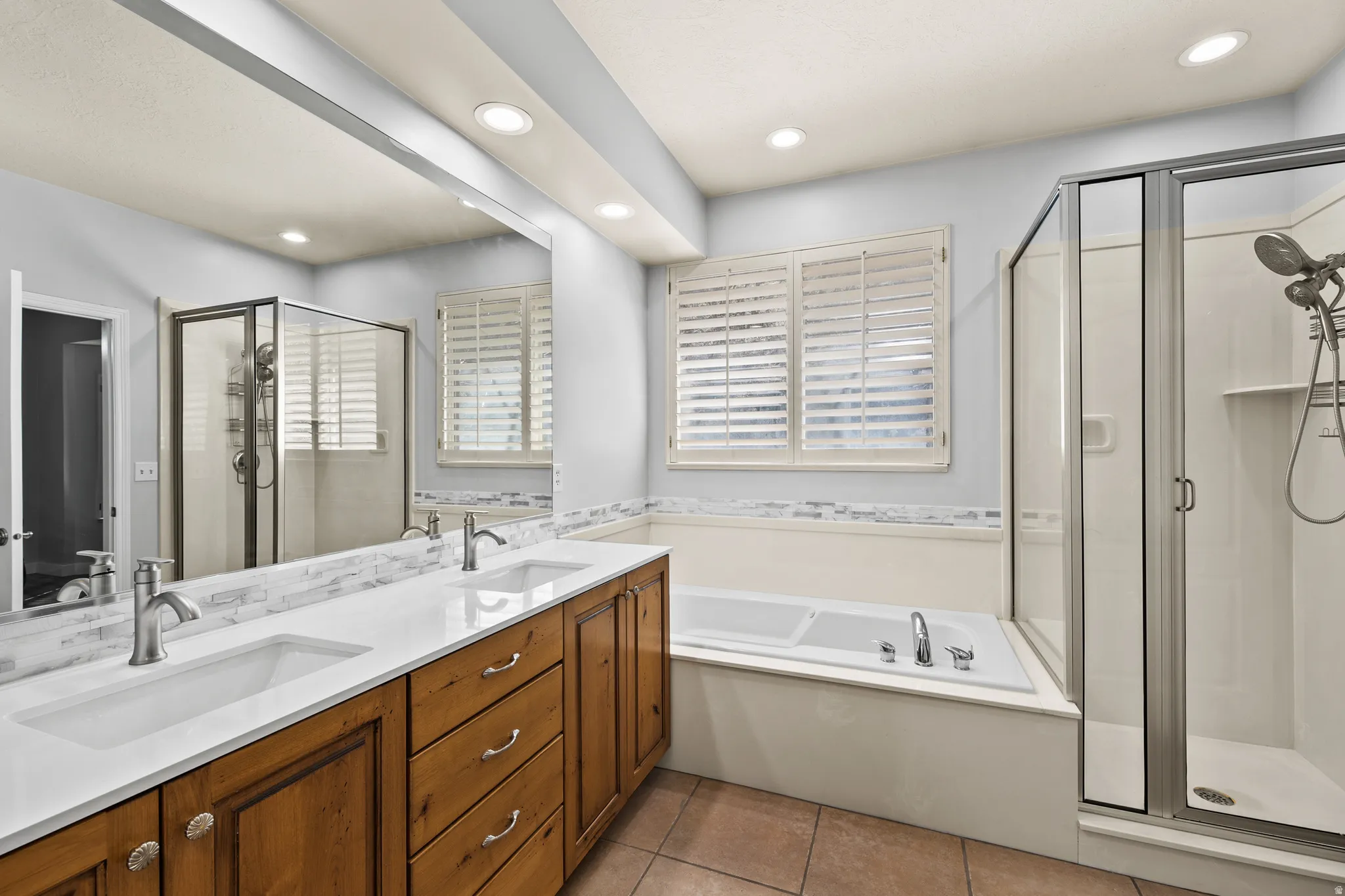 Bathroom with a shower stall, a garden tub, double vanity, light tile patterned flooring, and recessed lighting