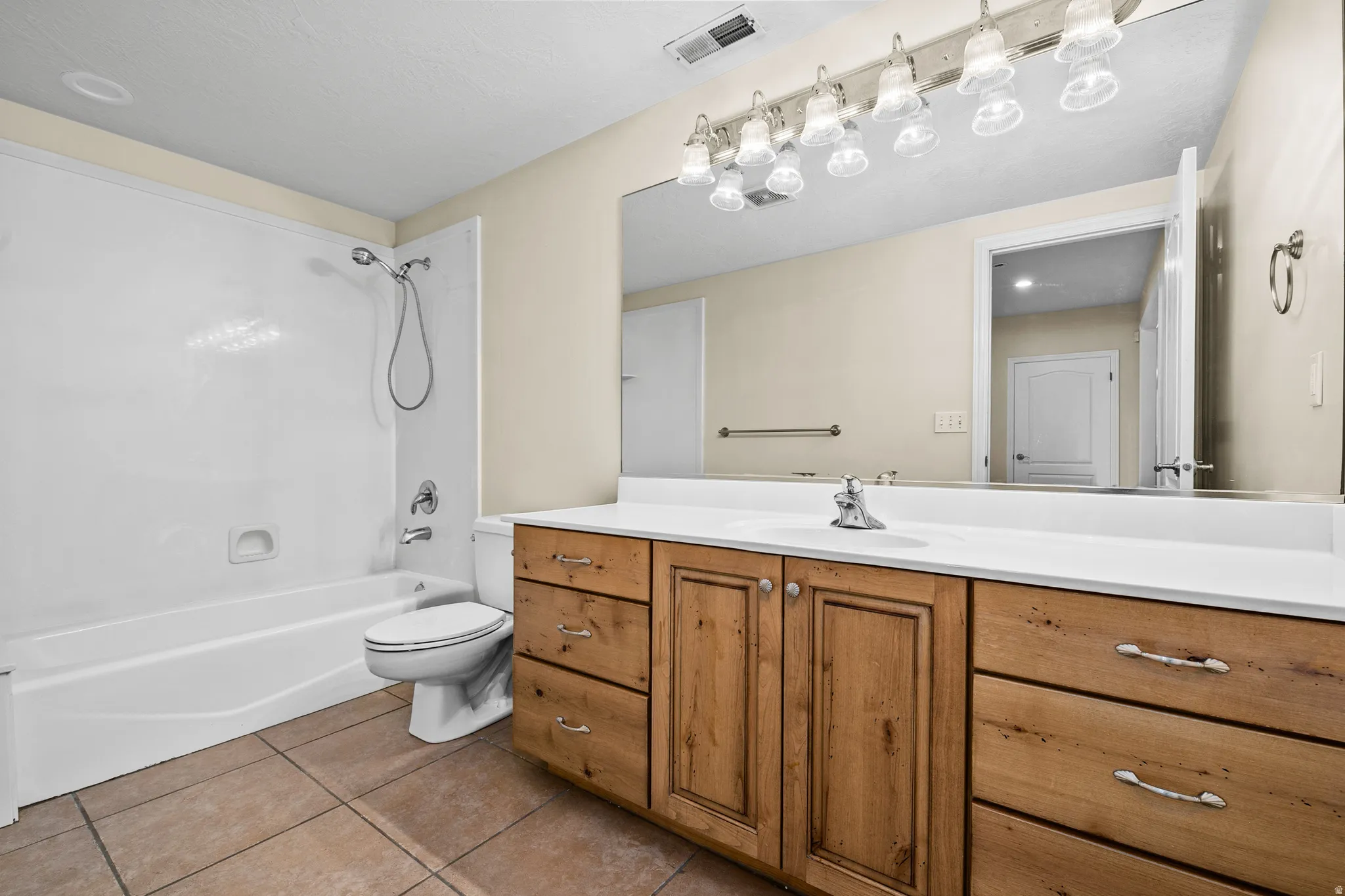 Bathroom with vanity, light tile patterned flooring, and shower / washtub combination