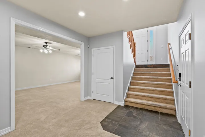 Staircase featuring carpet flooring, a ceiling fan, stone finish floors, and recessed lighting