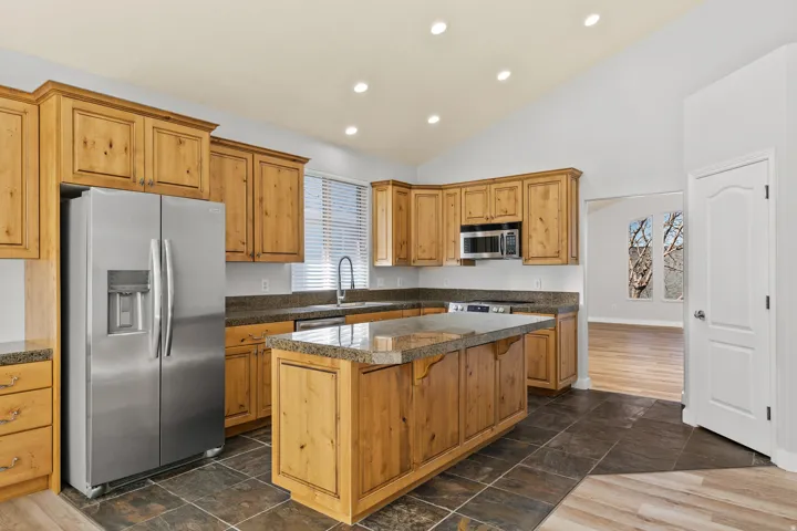 Kitchen featuring tile countertops, stainless steel appliances, a kitchen bar, a kitchen island, and recessed lighting