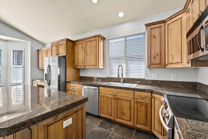 Kitchen featuring tile countertops, stainless steel appliances, lofted ceiling, recessed lighting, and a center island