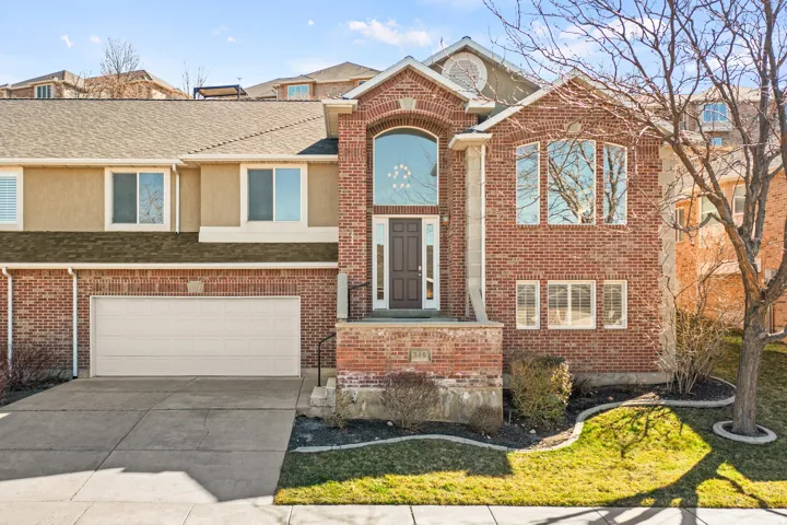 View of front of house featuring driveway, a garage, brick and stucco siding