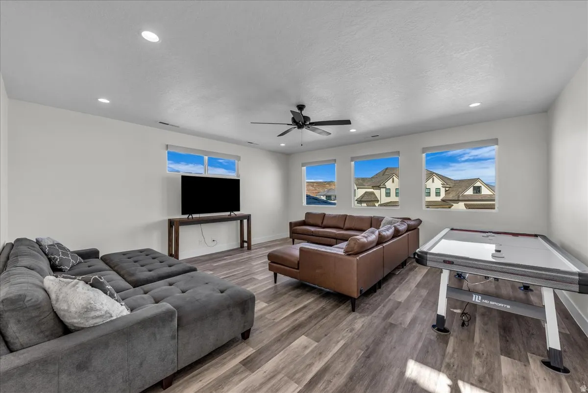 Living room with wood finished floors, recessed lighting, a ceiling fan, and a textured ceiling