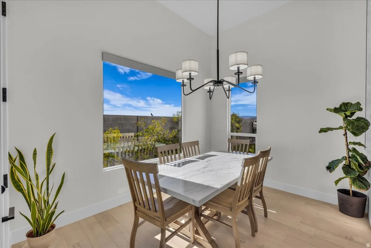 Dining space with light wood-style floors, lofted ceiling, and suspended lighting
