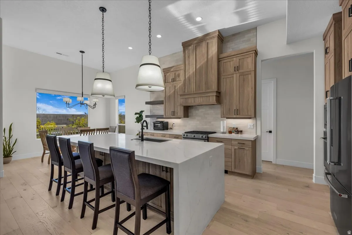 Kitchen featuring a breakfast bar area, light stone countertops, a large island, and stainless steel appliances