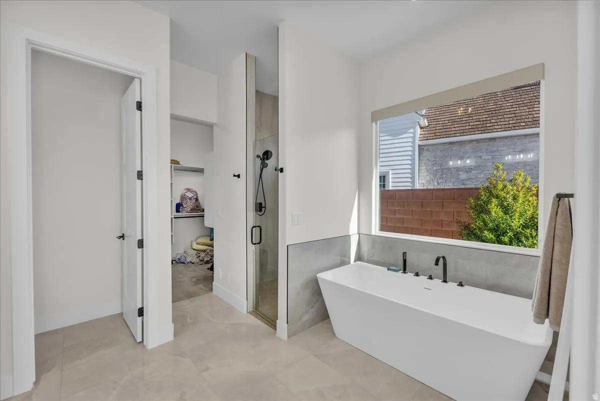 Bathroom featuring a shower stall, a freestanding tub, and tile walls