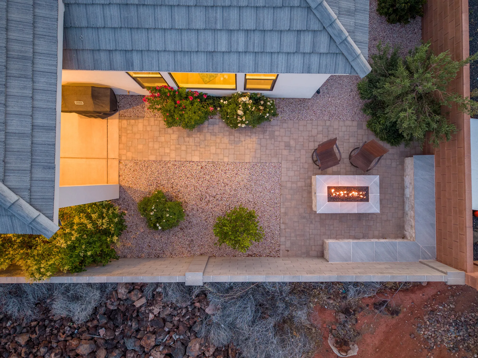 Paver patio featuring a built-in fire pit, integrated seating, and decorative landscaping