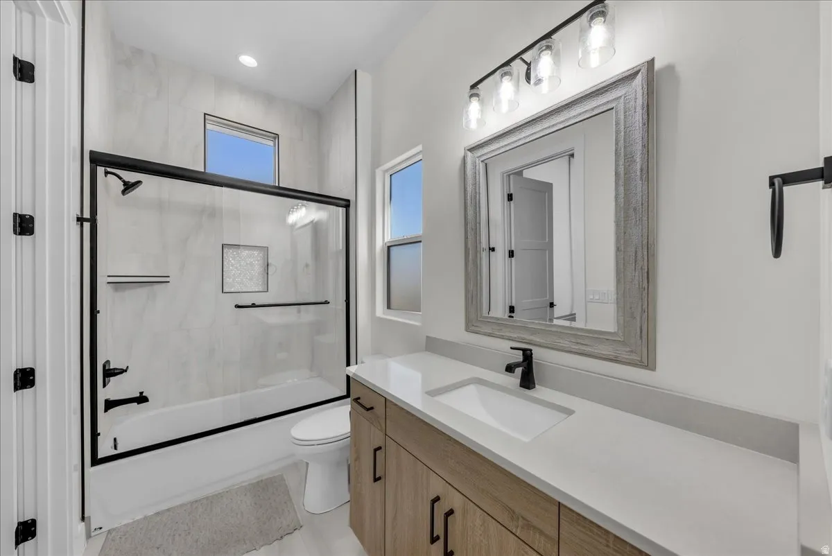 Full bathroom featuring vanity and shower / bath combination with glass door