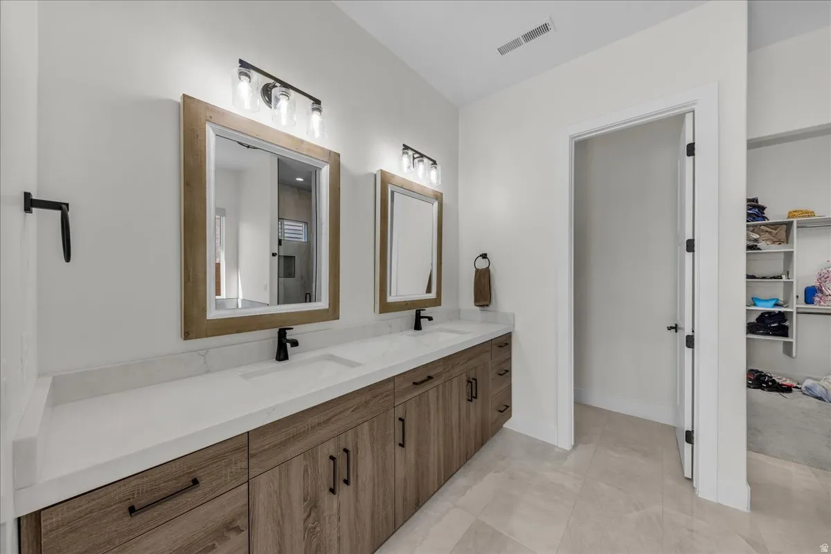 Full bath featuring double vanity, a spacious closet, and light tile patterned floors