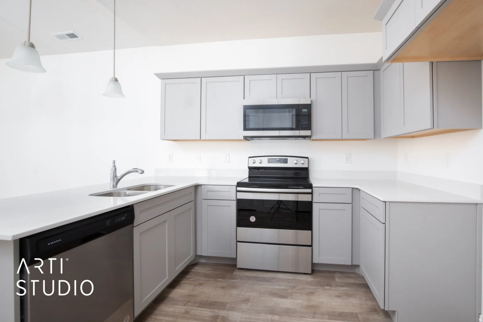 Kitchen featuring gray cabinets, stainless steel appliances, a peninsula, light stone countertops, and light wood-style floors