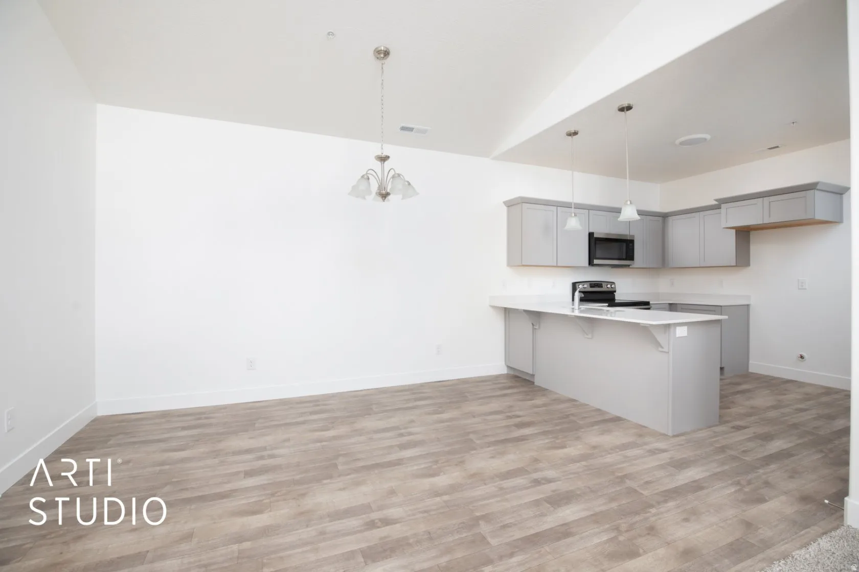 Kitchen with gray cabinets, a breakfast bar area, a peninsula, hanging lights, and stainless steel appliances