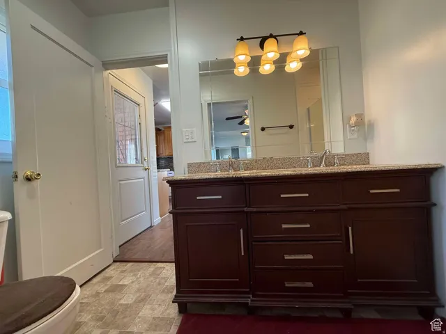 Bathroom featuring double vanity, stone finish floors, and ceiling fan