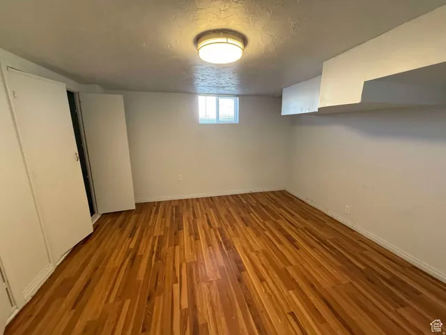 Basement with wood finished floors and a textured ceiling