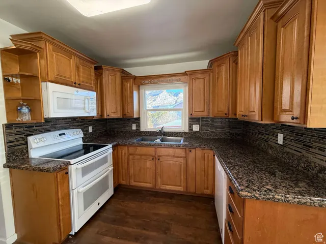 Kitchen featuring white appliances, open shelves, wood finish cabinets, and dark wood finished floors
