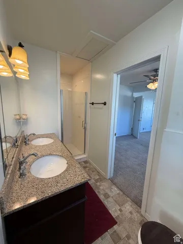Full bath with double vanity, light carpet, a stall shower, stone finish floors, and ceiling fan