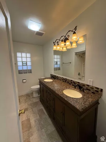 Bathroom featuring double vanity and stone finish flooring