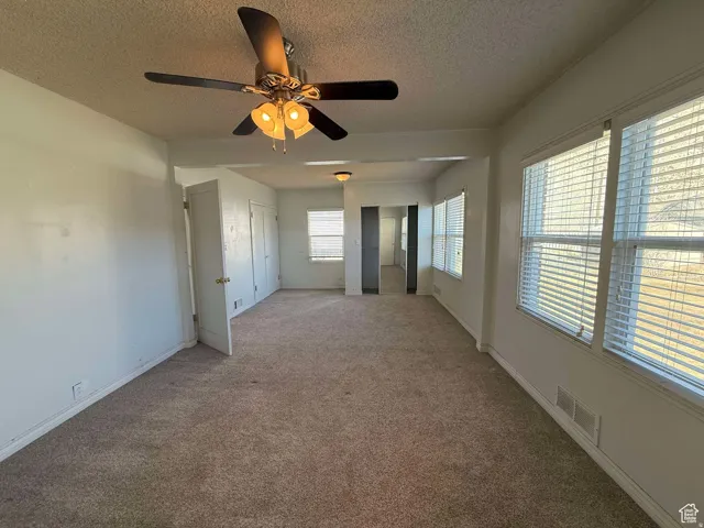 Unfurnished bedroom featuring a textured ceiling, ceiling fan, and carpet floors